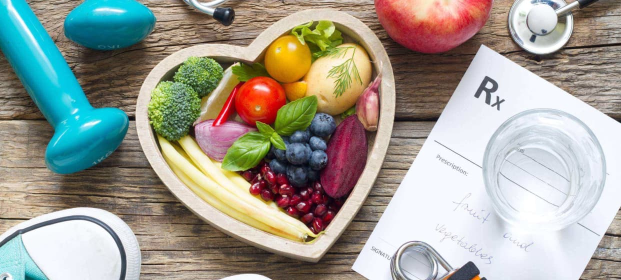 An image shows a heart-shaped tray filled with various fruits and vegetables, accompanied by a medical chart.
