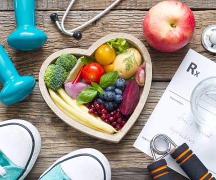 An image shows a heart-shaped tray filled with various fruits and vegetables, accompanied by a medical chart.