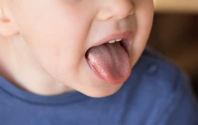 A picture of a kid sticking his tongue out of his mouth.