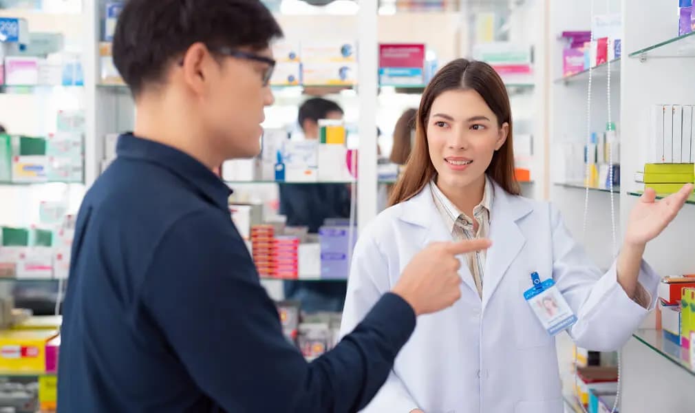In this image, a pharmacist is explaining about medicine to the patient.