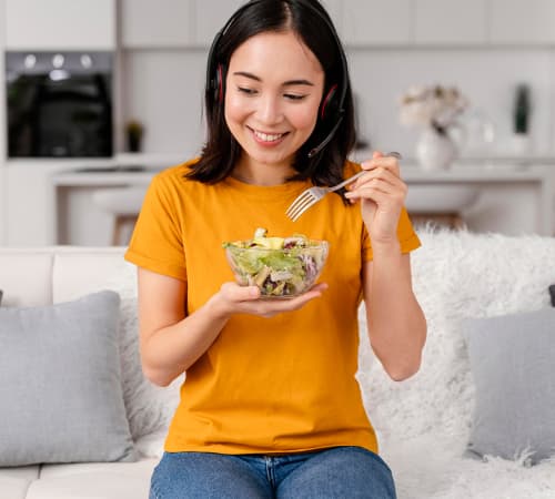 A picture of a woman holding a bowl of a healthy meal in one hand and a fork in the other.