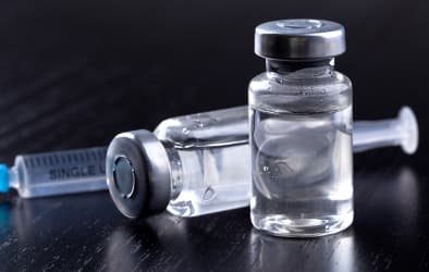 A picture of an injection and a vaccine bottle.