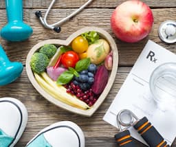 An image shows a heart-shaped bowl full of vegetables and fruits and a prescription on the table.
