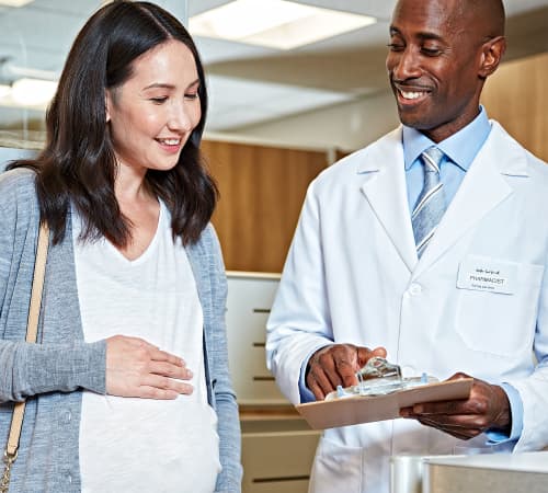 A picture of a doctor showing a report to a pregnant woman.