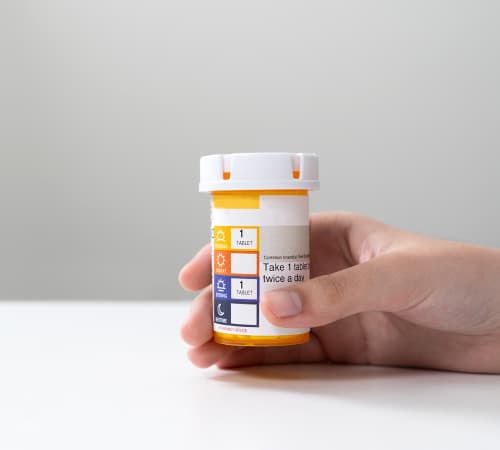 A picture of an Orange pill bottle held in hand.
