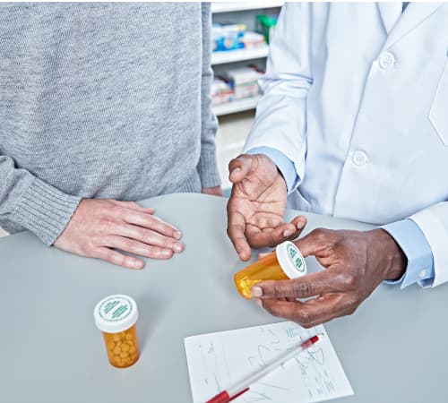 A picture of one person providing medication-related information to another person.
