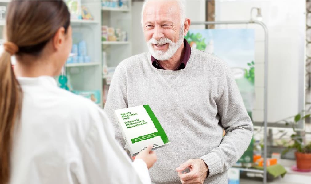 An image shows, doctor giving a Pharmacy book to an older man.
